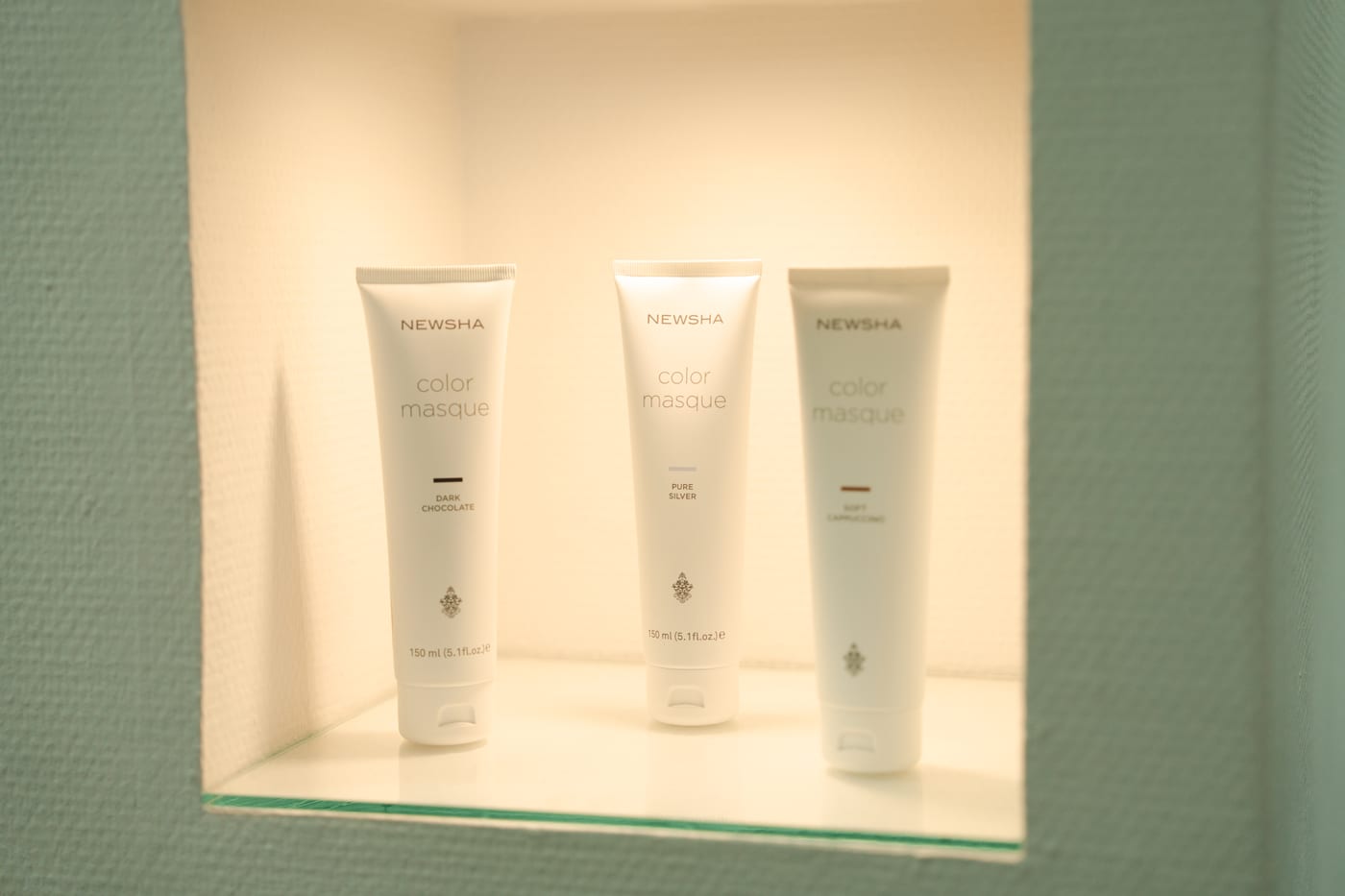 NEWSHA Color Masque — drei Pflegetuben in beleuchteter Nische